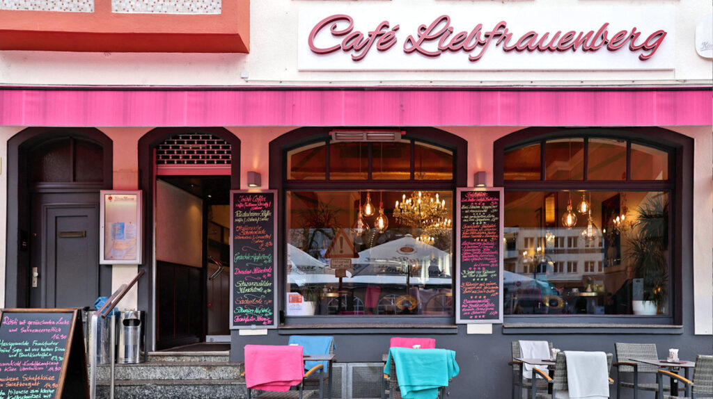 Pinkes Café, bunte Tafelbeschriftung, Deckenlampen.