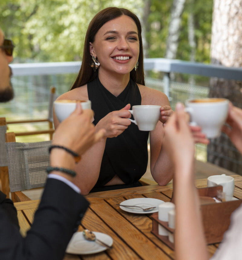 Lachende Freunde genießen Kaffee draußen.